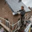 Zingueur européen installant des gouttières en zinc sur une maison belge